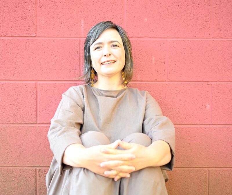 Poet Anna Lena Phillips Bell sitting against a pink wall